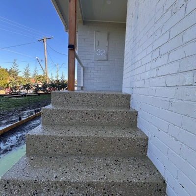Exposed aggregate steps at a white brick home