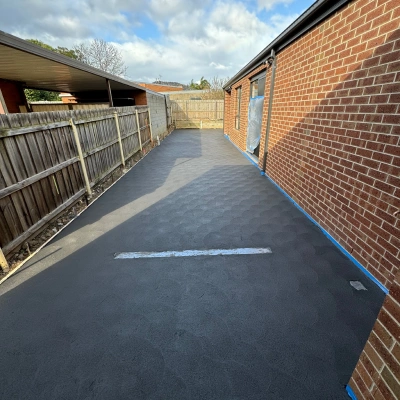 Dark concrete driveway alongside a brick wall
