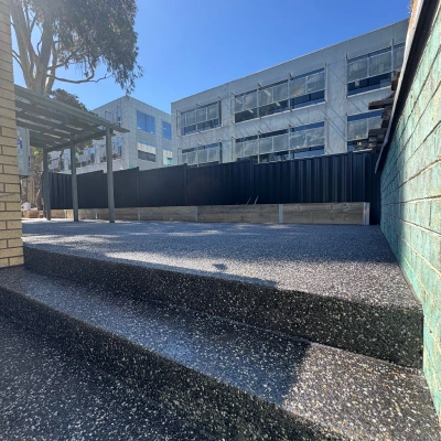 Dark exposed aggregate paving beside a commercial building