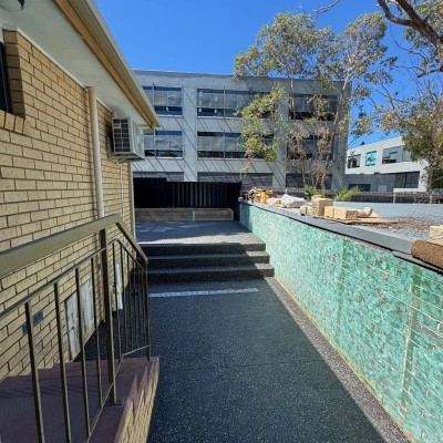 Exposed aggregate steps leading down beside a commercial building