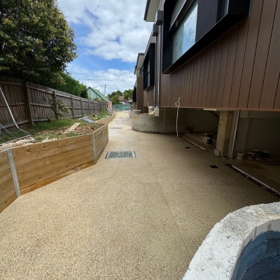 Exposed aggregate path beside a timber retaining wall